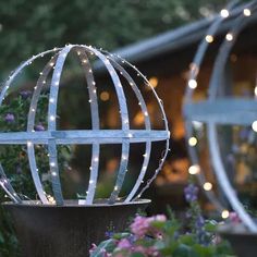 two metal spheres with lights on them in the garden