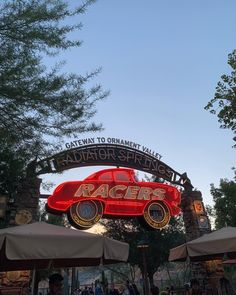 a red race car under a sign that reads racquets gateway to ornament valley