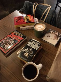 a table topped with books and a cup of coffee next to a bag on top of it