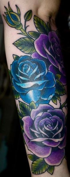 a woman's arm with tattoos on it and flowers painted on the back of her arm