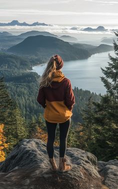 a woman standing on top of a mountain looking out at the ocean and mountains in the distance