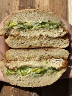 two halves of a sandwich with lettuce and meat in it being held by someone