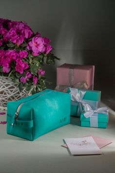 a blue bag sitting on top of a table next to pink flowers and gift boxes