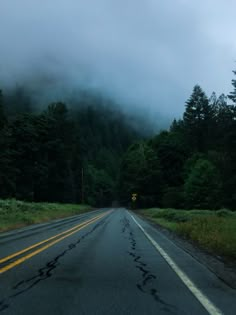 an empty road with trees and fog in the background