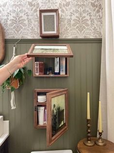 a bathroom with green walls and wooden shelves on the wall, along with a white toilet