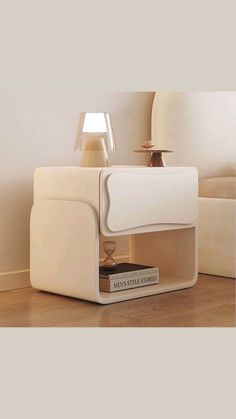 a white table lamp sitting on top of a wooden floor next to a book shelf