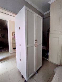 a large white cabinet sitting in the middle of a living room next to a bed