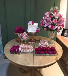 a table topped with two tiered cakes covered in pink flowers and small trays filled with food