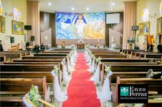 the interior of a church with pews and red carpeted aisle, decorated with flowers