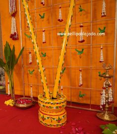 a vase filled with yellow candles sitting on top of a red cloth covered floor next to a wall