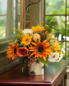 a vase filled with flowers sitting on top of a wooden table next to a window