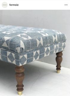 a blue and white patterned bench with wooden legs