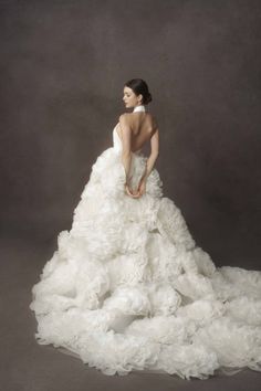 a woman in a white wedding dress is holding her hand on the back of her dress