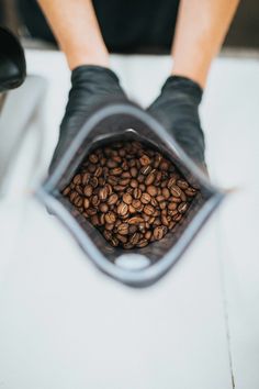 a person holding a bag full of coffee beans while sitting on a table with their feet up