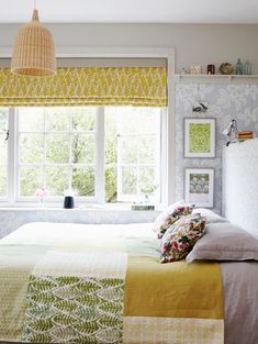 a bed sitting under a window next to a wall mounted light above it's headboard