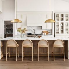 a kitchen with marble counter tops and gold pendant lights hanging from the ceiling over the island