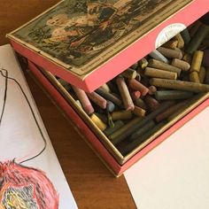 a box filled with colored crayons next to a drawing