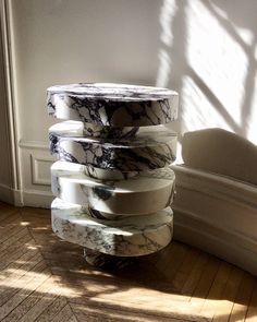 a stack of marble pedestals sitting on top of a hard wood floor next to a white wall