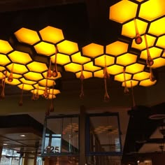 the lights are hanging from the ceiling above the tables in the restaurant, and they look like hexagonal cubes