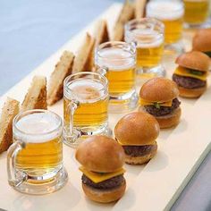 mini burgers and beer are arranged on a long serving platter with toasted bread