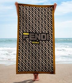 a person holding up a towel with the word fend roma on it at the beach