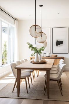 a dining room table with white chairs and art on the wall in front of it