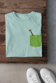 a t - shirt with a giraffe on it and some white shoes next to it