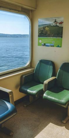 two green chairs sitting next to each other on a train near the water and a window