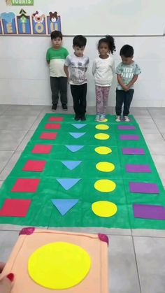 three children standing in front of a play mat