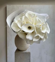 a white flower arrangement sitting on top of a cement block