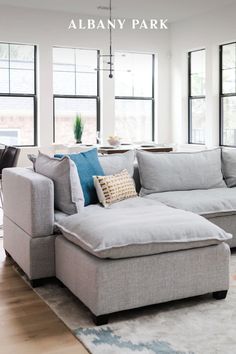 a living room filled with lots of furniture and large windows in the back drop down wall