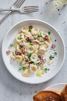 a white plate topped with pasta and peas