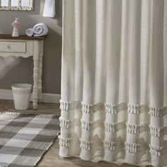 a bathroom with a checkered rug and white shower curtain in front of a mirror