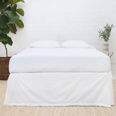 a white bed sitting next to a potted plant