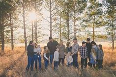 a group of people standing next to each other in a field with tall grass and trees