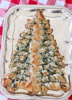 a christmas tree shaped pastry sitting on top of a glass plate with red and white checkered tablecloth