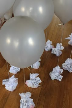 several white balloons with tags attached to them sitting on the floor next to each other