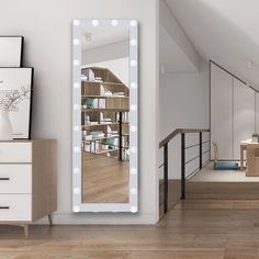 a large mirror with lights on it in a room next to a dresser and stairs