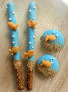 three decorated cookies sitting on top of a wooden table next to two donuts in the shape of dolphins