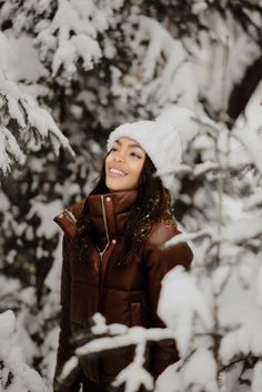 a woman standing in front of snow covered trees