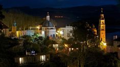 a night time view of a town with lights on and trees in the foreground