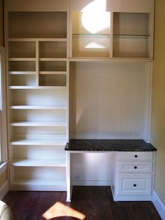 an empty room with white shelves and drawers