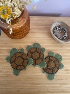 three turtle coasters sitting on top of a wooden table next to a potted plant