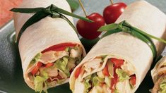 two wraps filled with chicken, lettuce and tomatoes on a green platter