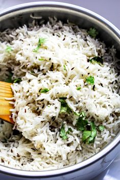 a metal bowl filled with white rice and herbs