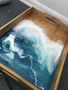 a wooden box filled with blue and white liquid on top of a black floor next to a rug