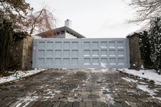 a driveway with snow on the ground and a large gate that has been built into it