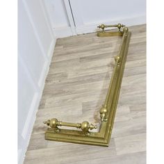 a long gold mirror frame laying on the floor in front of a door with two handles