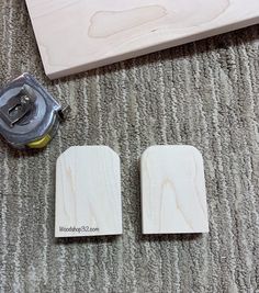 two pieces of wood sitting on top of a carpet next to a stapler and tape dispenser