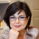 a woman wearing glasses sitting at a table